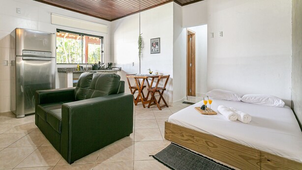 Quarto compacto com cama, sofá, mesa de jantar e cozinha compacta.