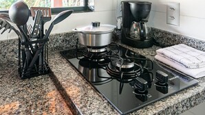 Een keuken met een fornuis, een koffiezetapparaat en keukengerei.