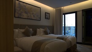 Une chambre d’hôtel avec deux lits, une grande fenêtre et un tableau au mur.