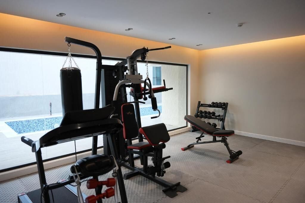 A home gym with a punching bag, weight bench, and various exercise equipment.