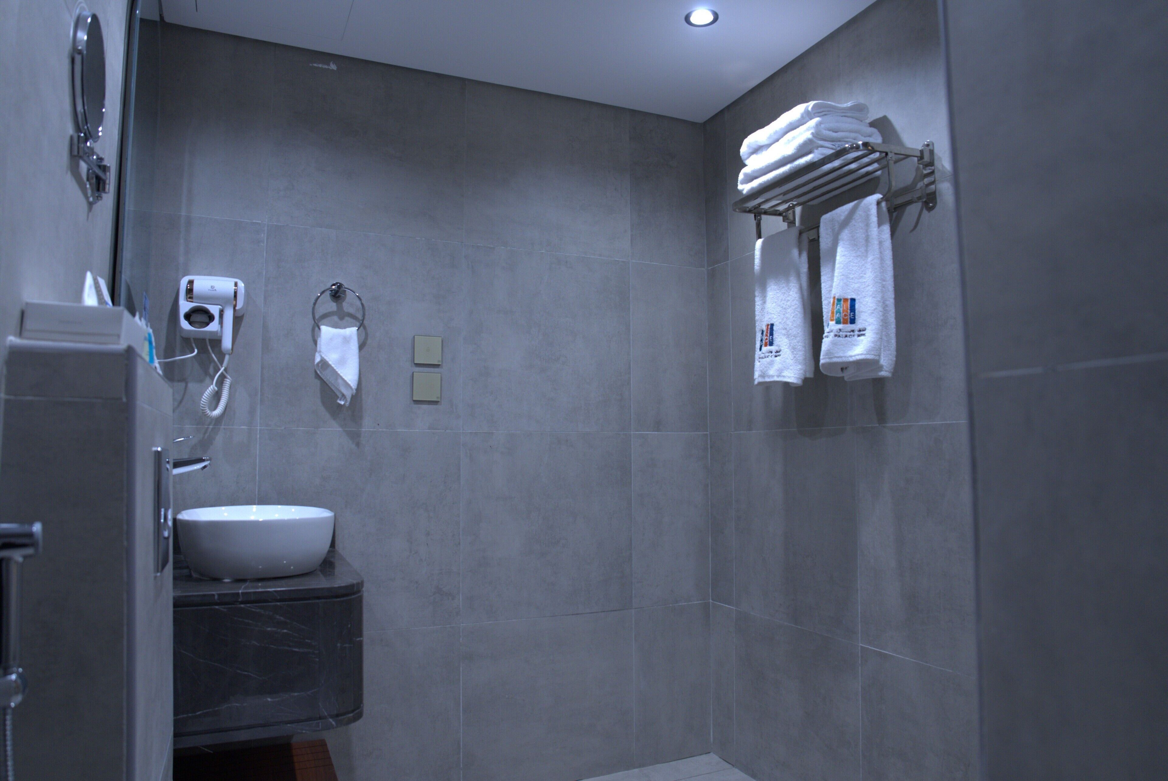 A modern bathroom with a sink, towel rack, and a toilet paper holder.