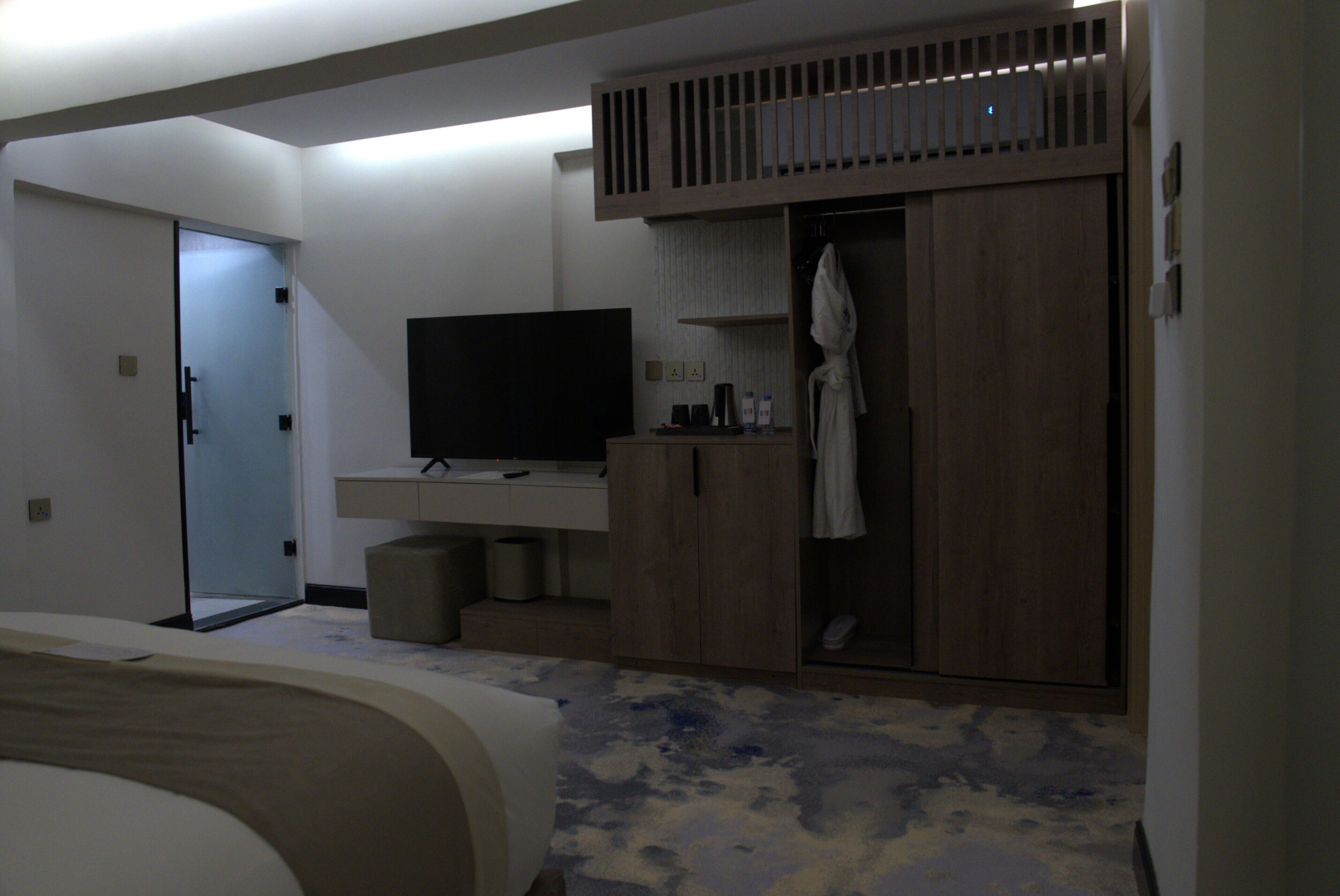 A hotel room with a bed, a TV, a wardrobe, and a bathroom.