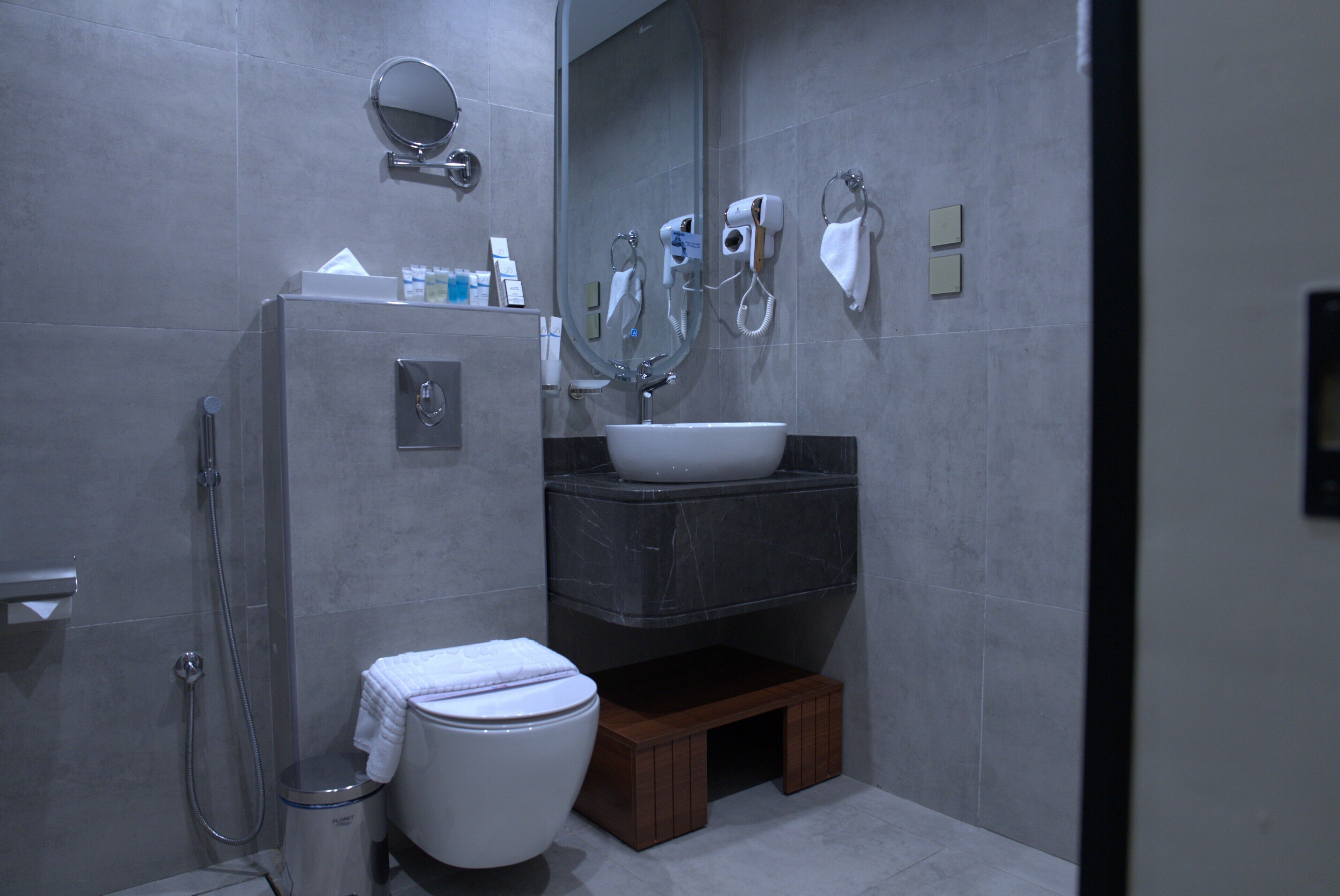 Et moderne badeværelse med bruser, toilet, håndvask og spejl.