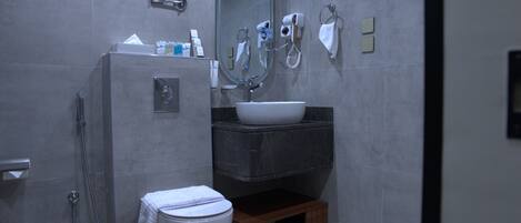 Uma casa de banho moderna com chuveiro, sanita, lavatório e espelho.