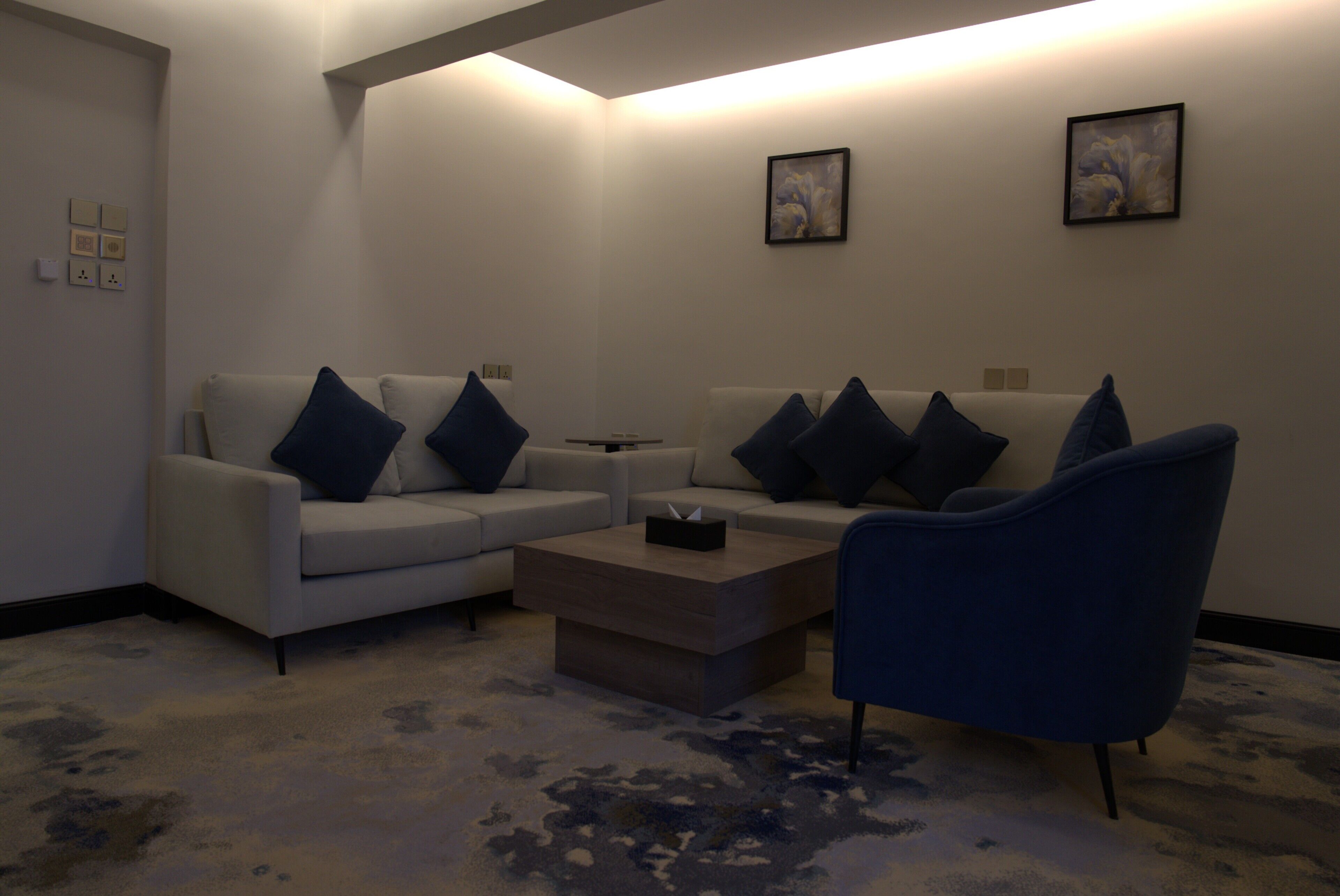 A modern living room with a sofa, armchair, coffee table, and artwork on the walls.