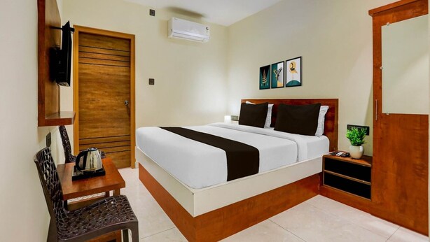 Habitación de hotel con cama, escritorio, silla, armario y aire acondicionado instalado en la pared.