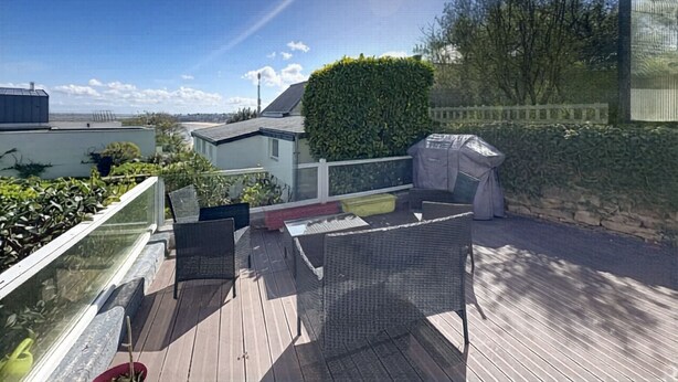 Un terrazzo con mobili da esterno, un barbecue e vista sul mare.