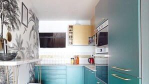 Una cucina moderna con mobili color petrolio, un frigorifero nero e un forno a microonde.