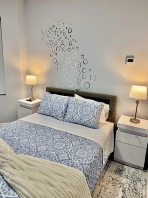 Une chambre moderne avec un grand lit, deux tables de chevet et une œuvre d’art murale.