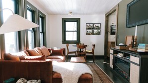 A cozy living room with a brown sofa, a white throw blanket, a wooden coffee table, and a fireplace. - Luxury Lakefront Cabin in Hope - Close to Camden & Rockland (Hope)