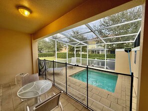 Ein überdachter Außenbereich mit Pool, Tisch und Stühlen.