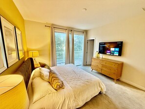 Ein Schlafzimmer mit Bett, Kommode, Fernseher und Balkon.