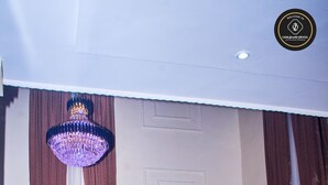 A modern living room with a chandelier, leather sofas, a flat-screen TV, and a large framed picture on the wall. - Ozigrand Hotel (Benin City)