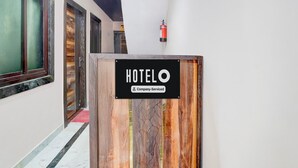 Hoteleingang mit Holzschild, Feuerlöscher und einem Korridor mit Türen.