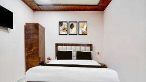 Ein Schlafzimmer mit einem Bettgestell aus Holz, einem an der Wand montierten Flachbildfernseher und drei gerahmten Kunstwerken über dem Bett.