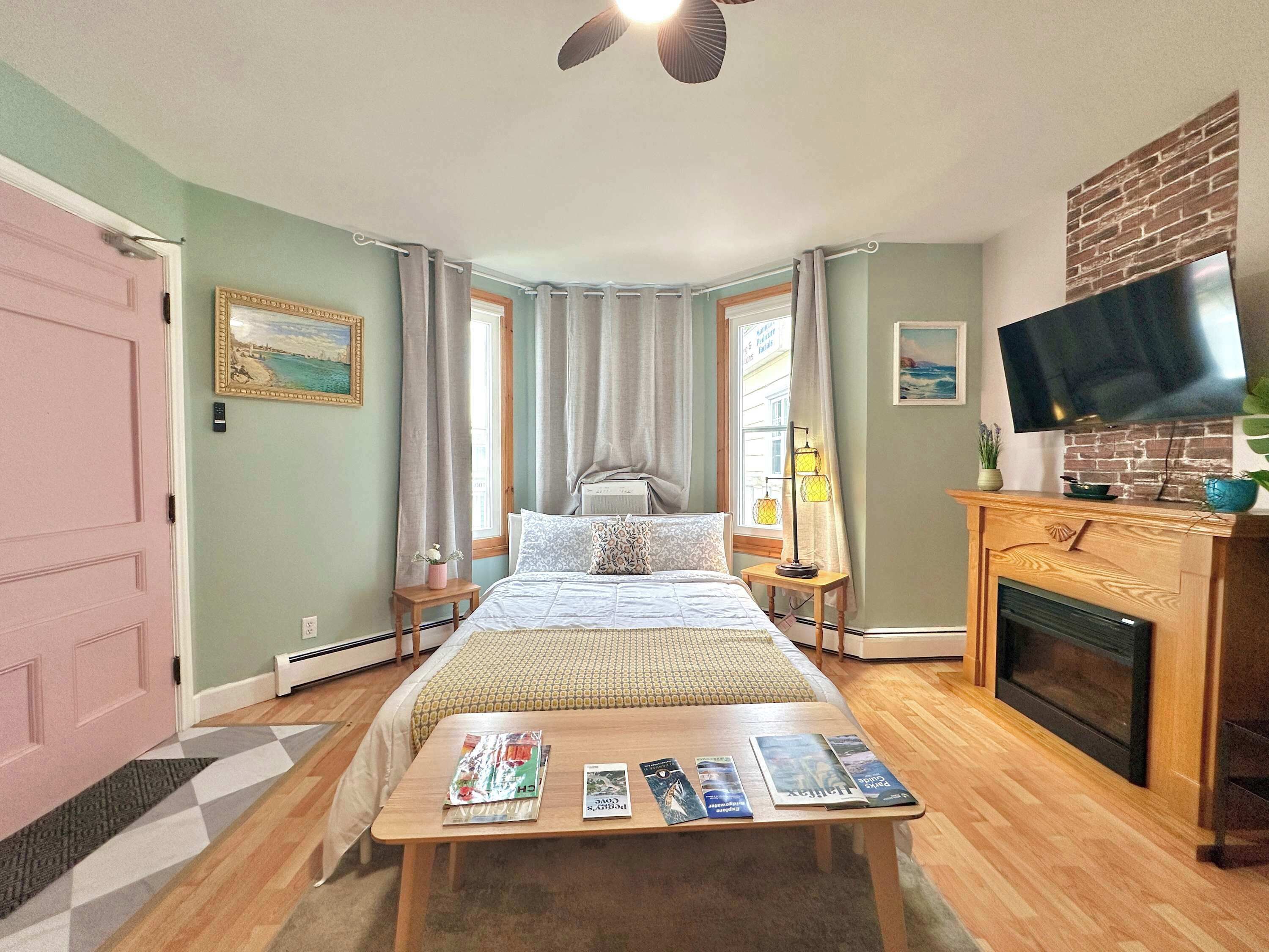 Une chambre à coucher comprenant un lit, une télévision, une cheminée, une fenêtre avec des rideaux et une table de chevet avec une lampe.
