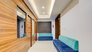 Um corredor com parede de madeira, um sofá azul e uma porta de vidro.