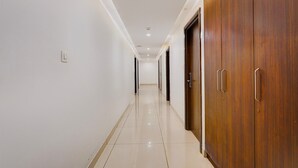 Um corredor com um armário de madeira à direita, um interruptor de luz à esquerda e uma porta no final.