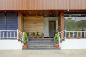 Entrada de edificio con fachada de madera, escalones y plantas en macetas.