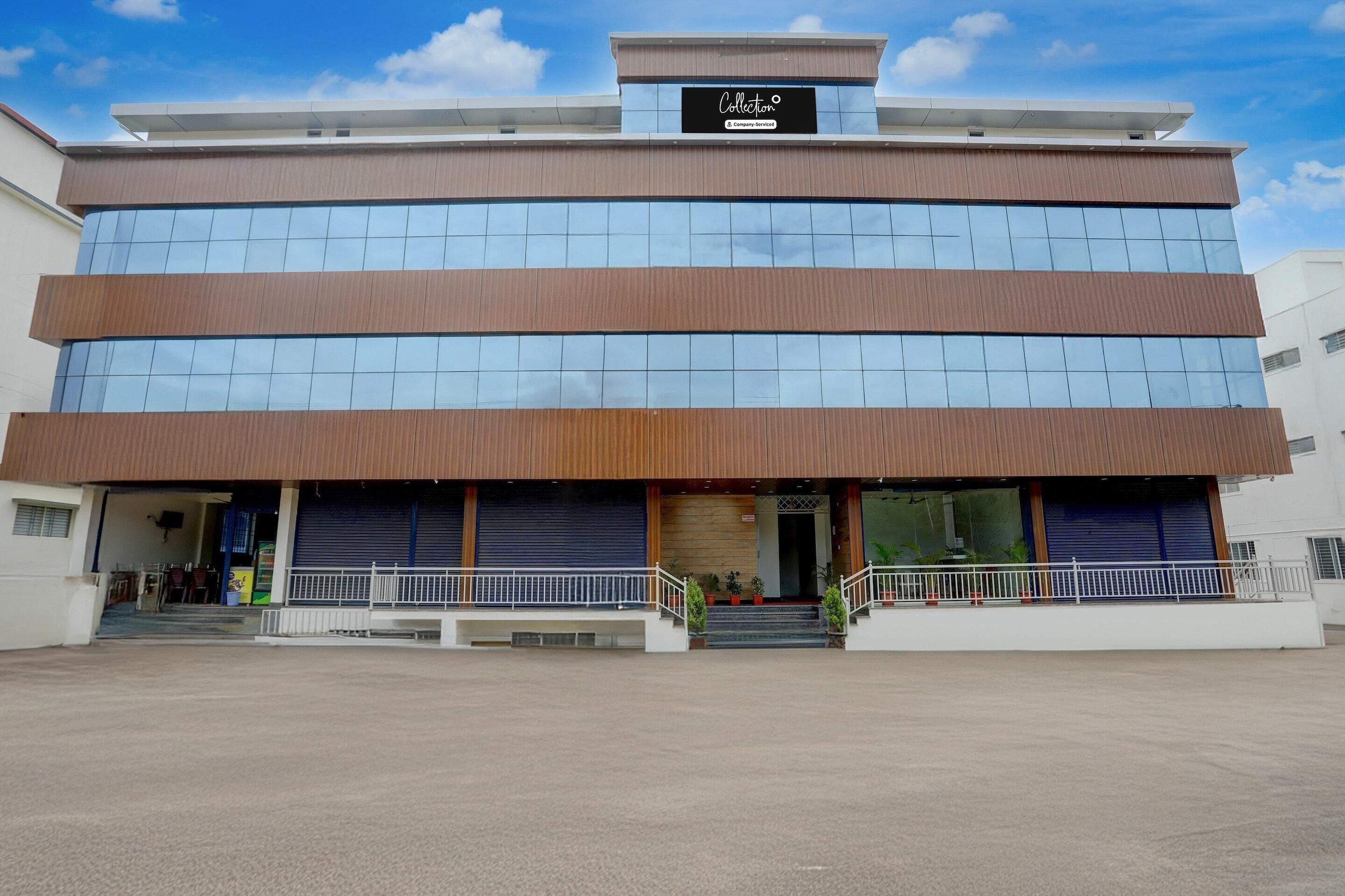 A modern building with a sign reading 'Collection.' It has multiple floors, large windows, and a covered entrance area with steps.