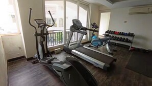 Et træningscenter med løbebånd, crosstrainer og en vægtstang med håndvægte.