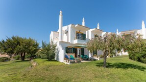 Een witte villa met balkon, zwembad en tuin.