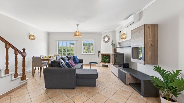 Een ruime woonkamer met een bank, televisie en eettafel.