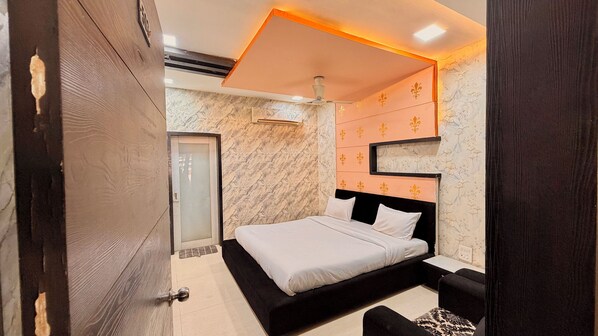 A bedroom with a bed, a nightstand, a wall-mounted shelf, and a door. - Shubh Kaaraj Resort (Indore)