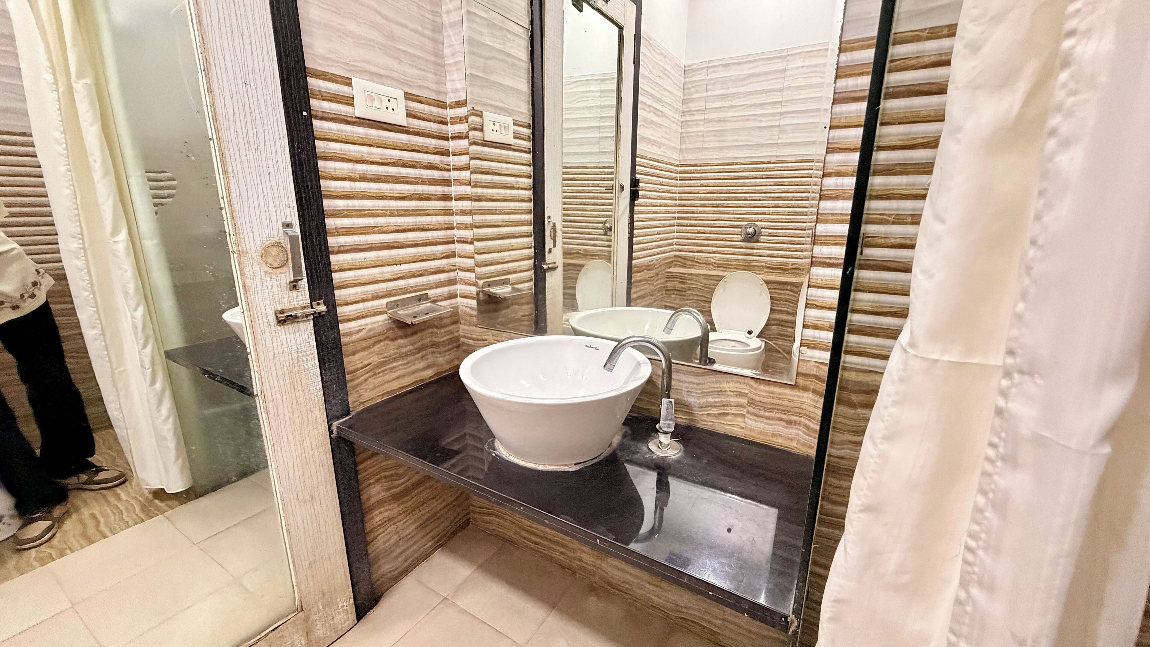 Un bagno con un lavandino bianco, uno specchio e un water.