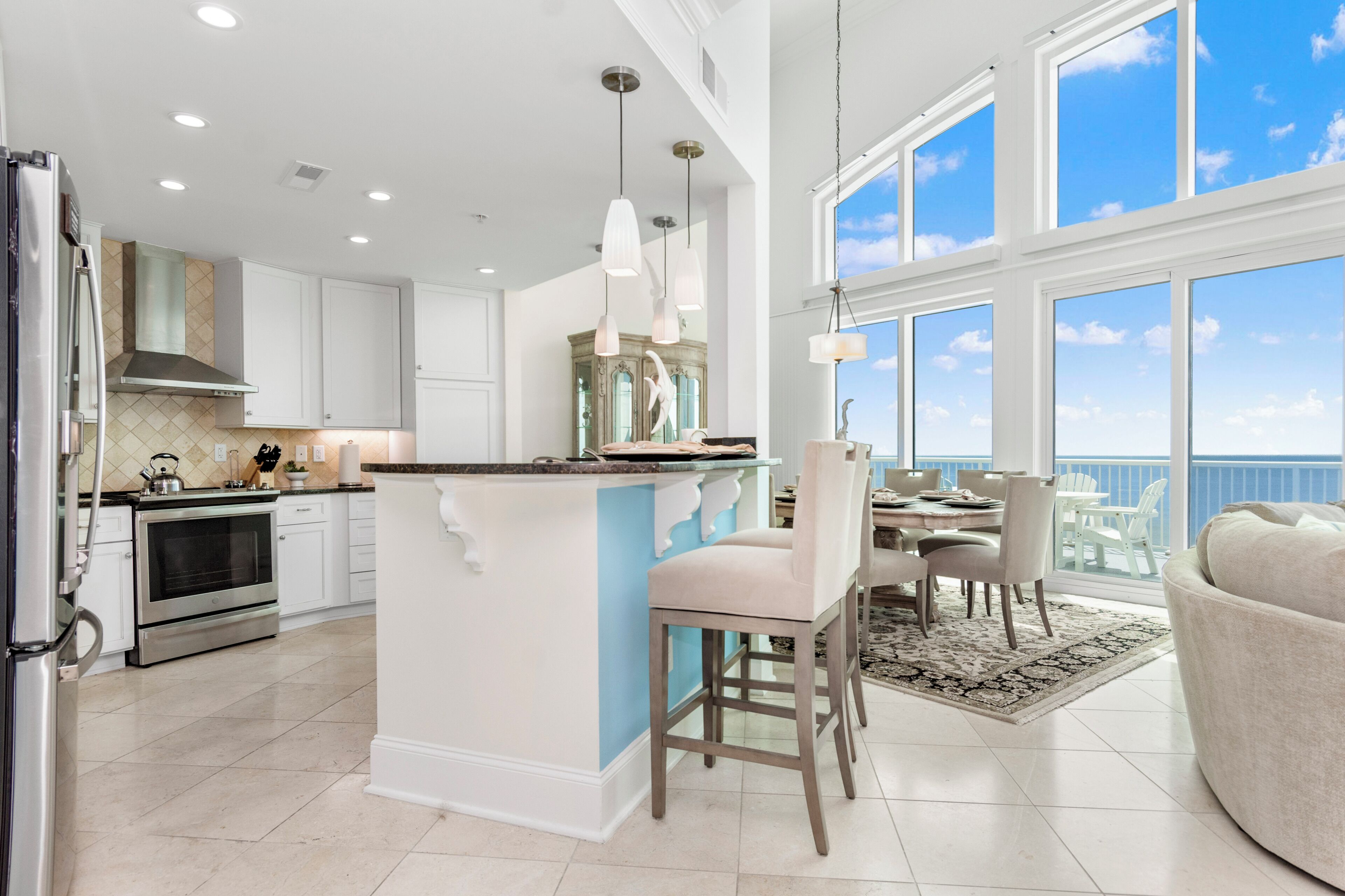 A modern kitchen with white cabinets, a central island, and pendant lighting.
