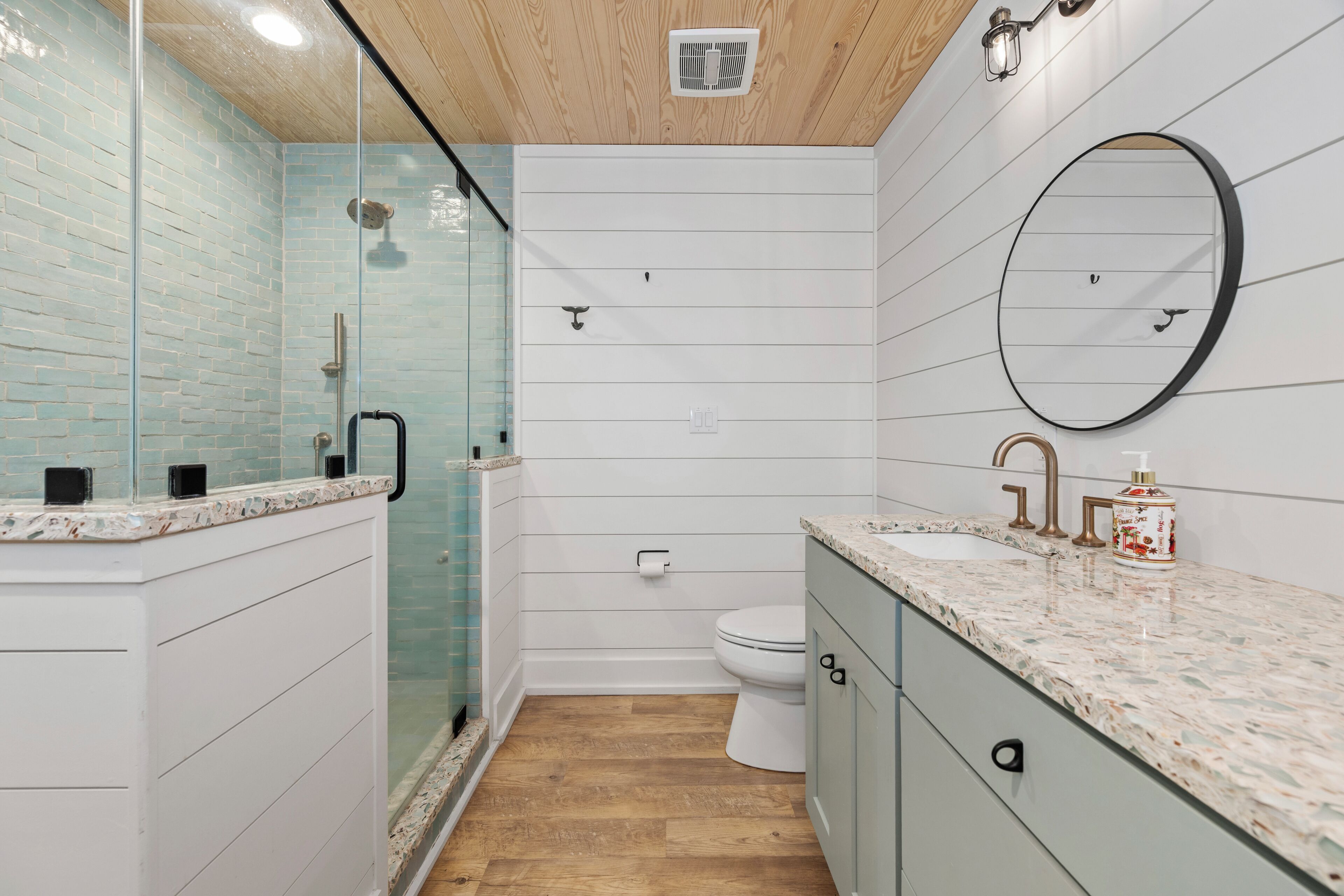 A modern bathroom with a glass shower enclosure, a toilet, and a sink with a marble countertop.