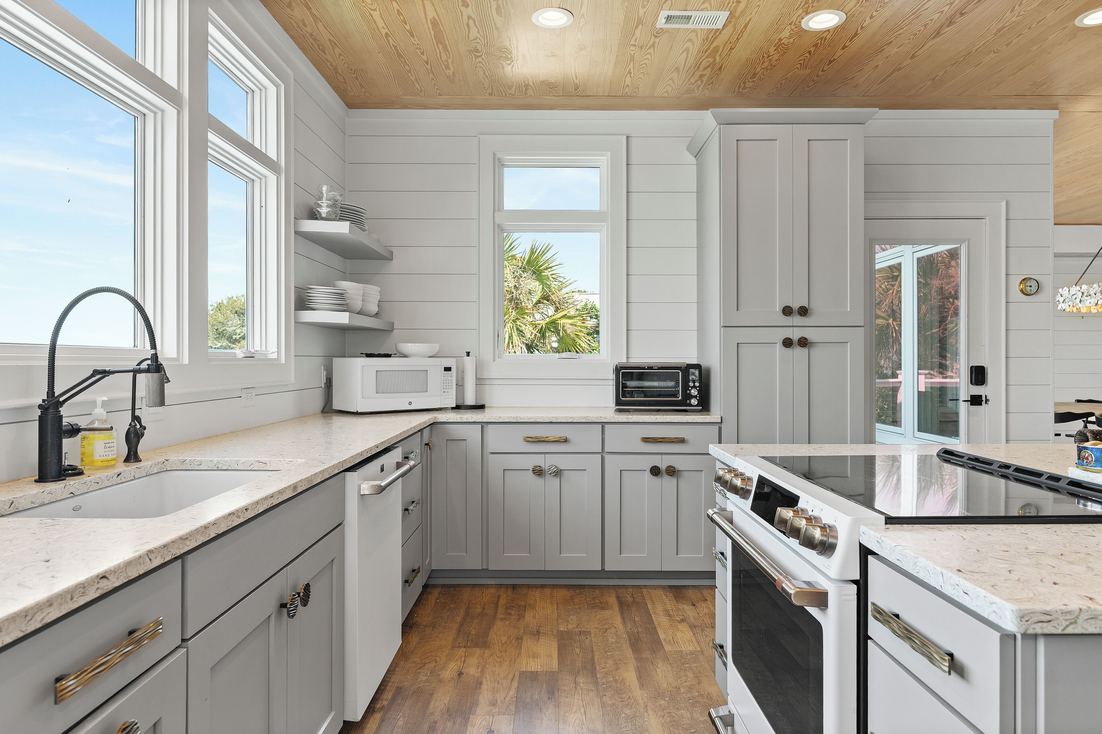 A modern kitchen with white cabinets, a microwave, a stove, and a sink.