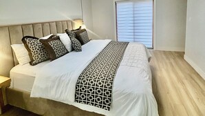 Una camera da letto con un lucernario, un letto con copriletto decorato, un comodino e una finestra con persiane.