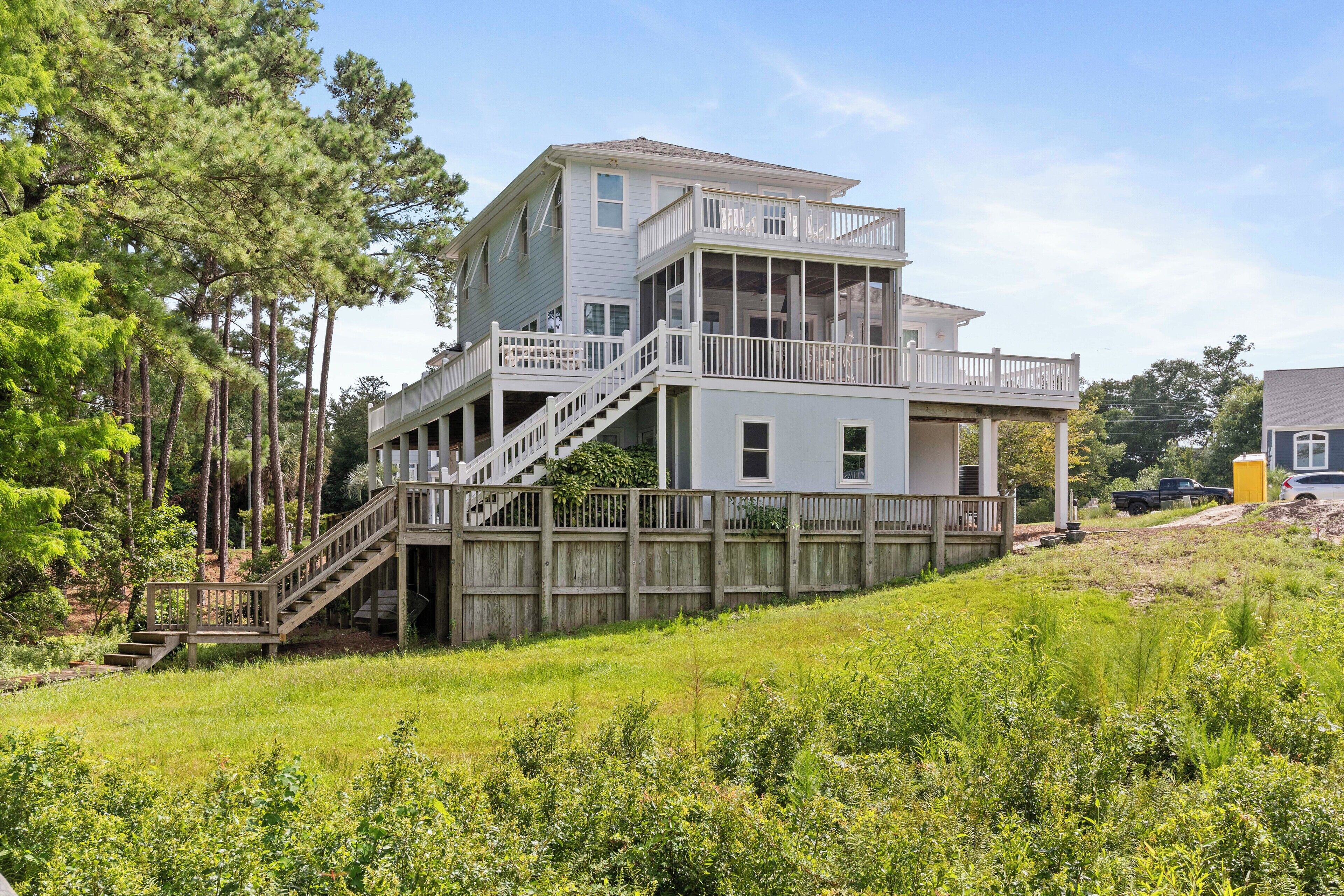A two-story house with a deck, a staircase, and a fenced yard.