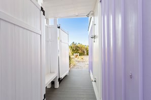 Ein Korridor mit weißen und violetten Wänden, der zu einem Außenbereich mit einem Steinweg und Grünflächen führt.