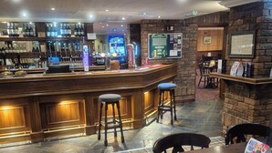 Eine Bar mit Hockern, einer Theke und verschiedenen Flaschen und Gläsern.