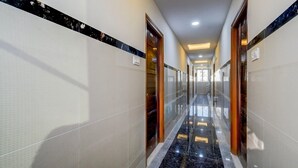 A hotel hallway with tiled walls, a marble floor, and wooden doors. - Deluxehotel Lanco Hills (Hyderabad)