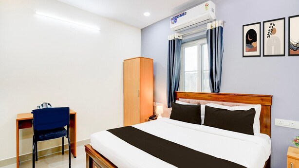 A bedroom with a bed, a desk, a wardrobe, and a window with curtains. - Deluxehotel Lanco Hills (Hyderabad)