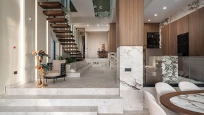 Un interior moderno con una escalera de m ármol, una zona de comedor con mesa de mármol y una cocina con armarios de madera.