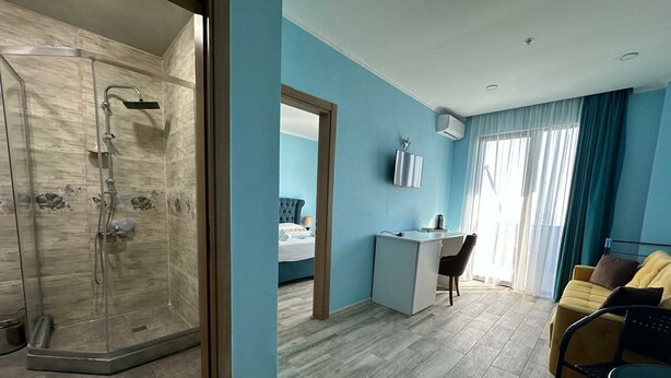 Habitación de hotel con ducha, cama, escritorio y silla.