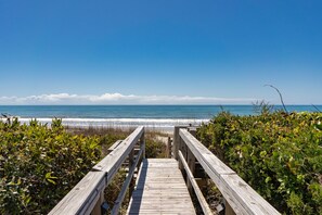 Una passerella di legno che conduce a una spiaggia sotto un cielo sereno.