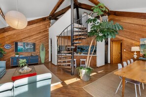 A spacious loft with a wooden interior, a spiral staircase, a dining area, and a kitchen.
