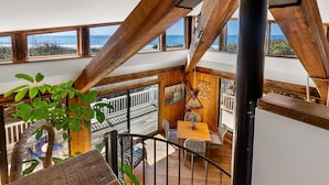 A wooden staircase leading to a balcony with a view of the ocean. - Oceanfront Treehouse Retreat | Private Beach Walkw (Pine Knoll Shores)