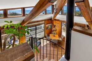 A wooden staircase leading to a balcony with a view of the ocean.