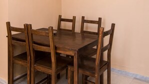 Un comedor con una mesa y sillas de madera, una lámpara colgante y una pared lisa.