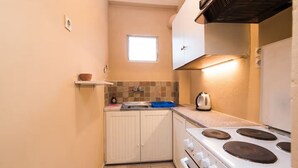 Una cocina compacta con estufa, lavamanos y un ventanal pequeño.