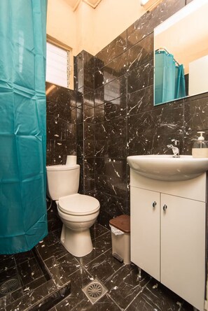 A bathroom with a toilet, sink, and mirror.