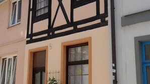 Un edificio con il numero '5' sulla facciata, una finestra con un motivo a griglia e una porta a griglia.