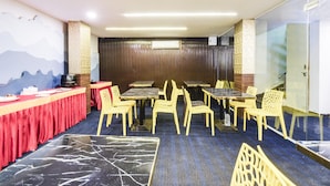 A conference room with tables and chairs, a red tablecloth, and a mural on the wall. - Deluxe Hotel Blue Petals (Hyderabad)