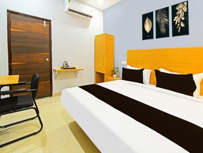 Ein Hotelzimmer mit Bett, Schreibtisch, Stuhl, Kleiderschrank und Wandbildern.